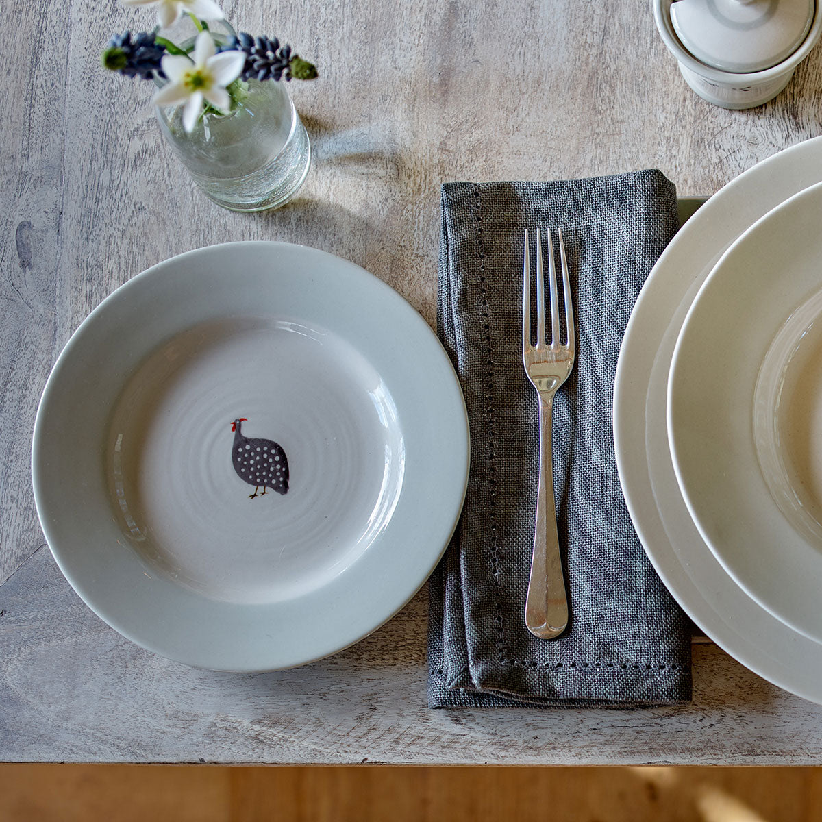 Guinea Fowl side plate flat-laid with fork and folded napkin