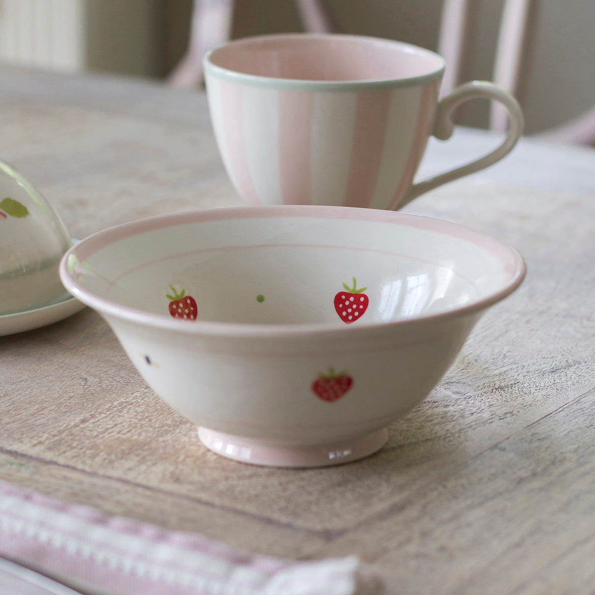 Strawberry pudding bowl with a pink striped mug on a painted surface