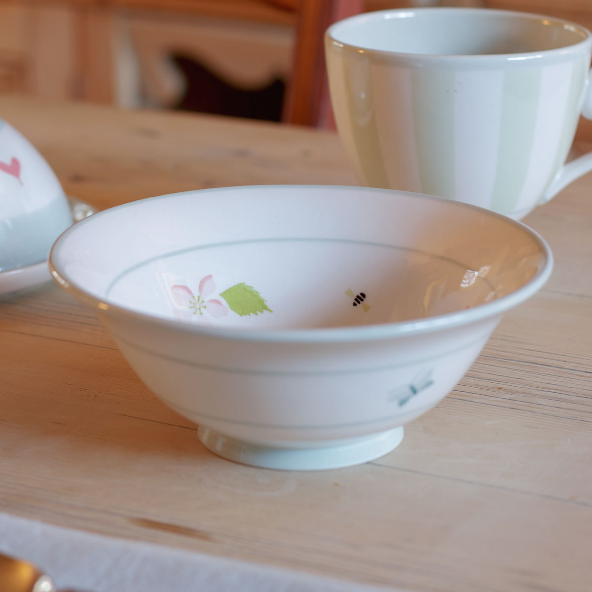 Apple Blossom pudding bowl on a pine table with a mug behind