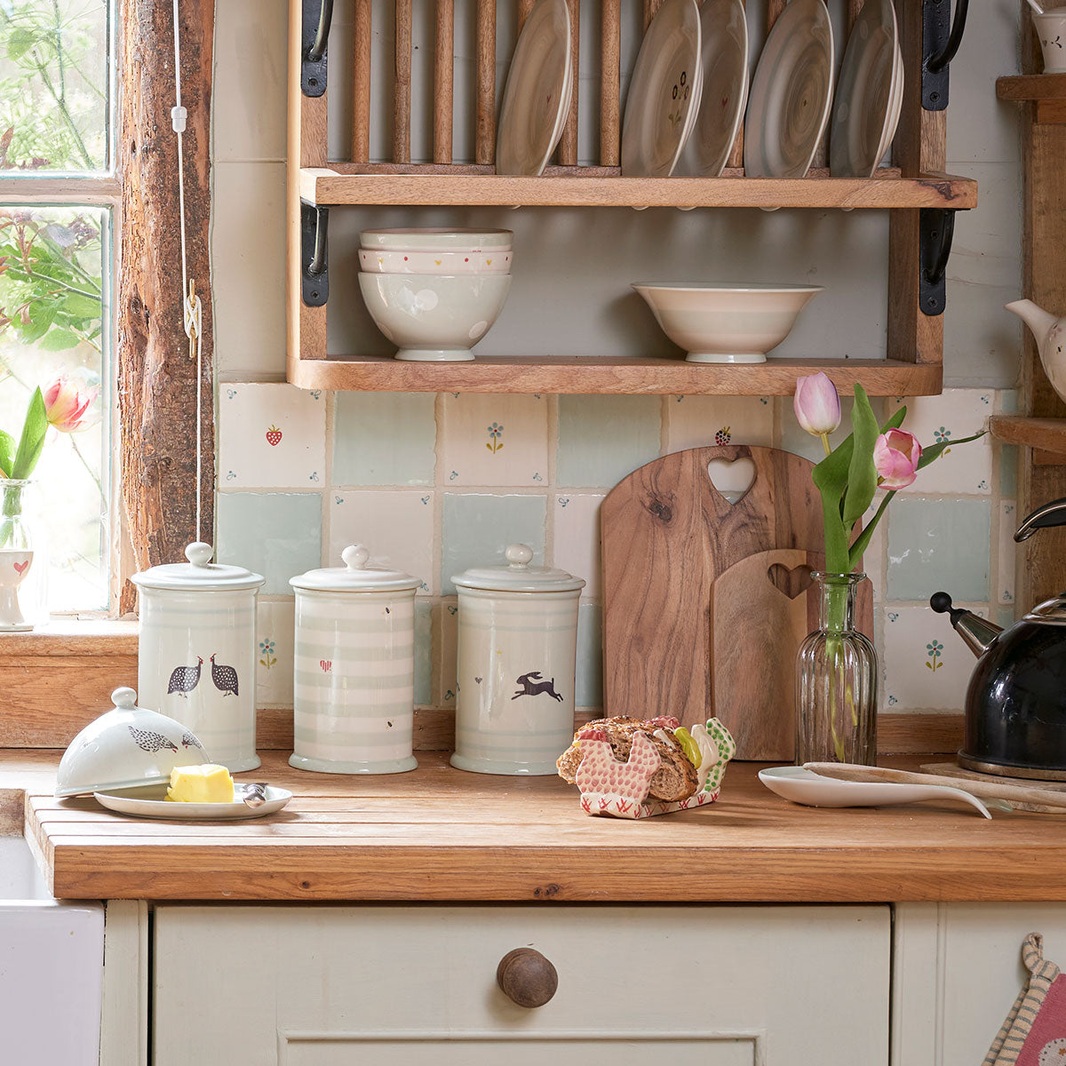 Guinea Fowl storage jars on a kitchen worktop with tulips and plate rack