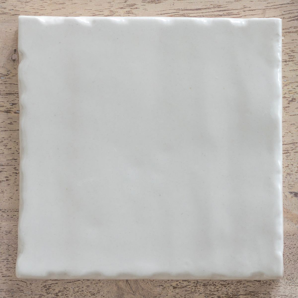 Single plain ivory ceramic tile with a softly rippled glazed surface