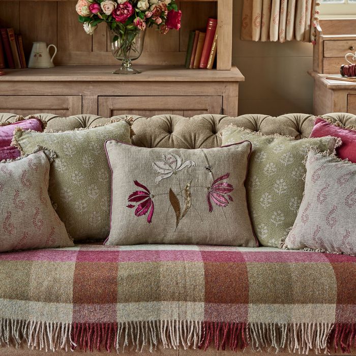 Parrot Tulips cushion among cushions on a sofa in front of a bookcase