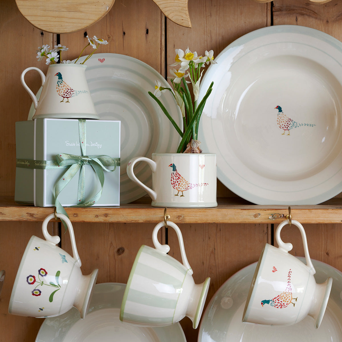 Pheasant mugs and plates on a dresser shelf with ribboned gift boxes