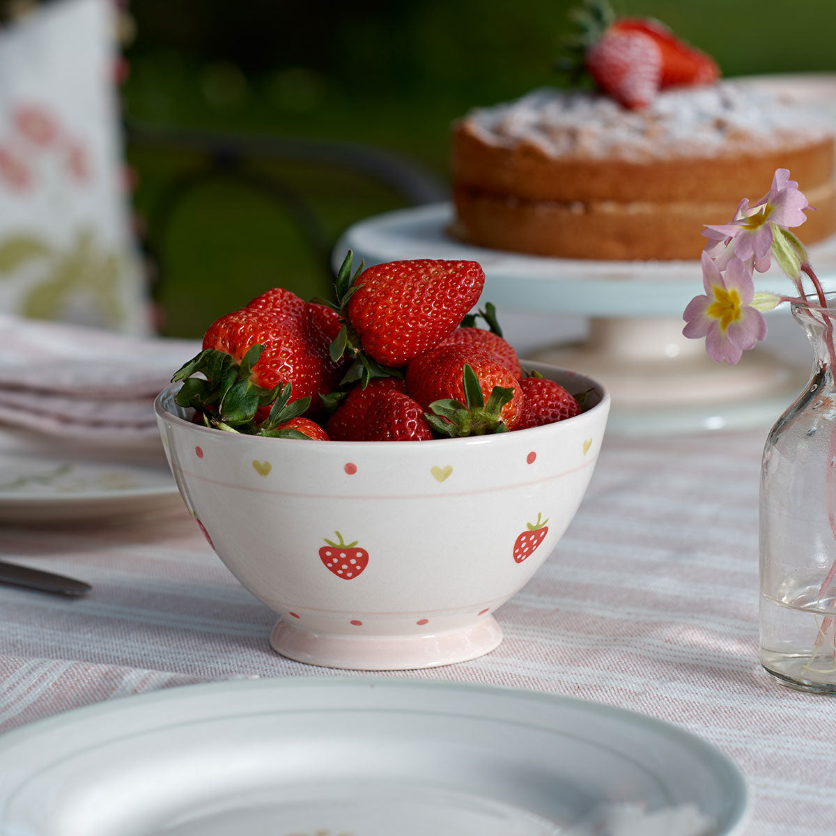Strawberry French bowl filled with strawberries beside a cake