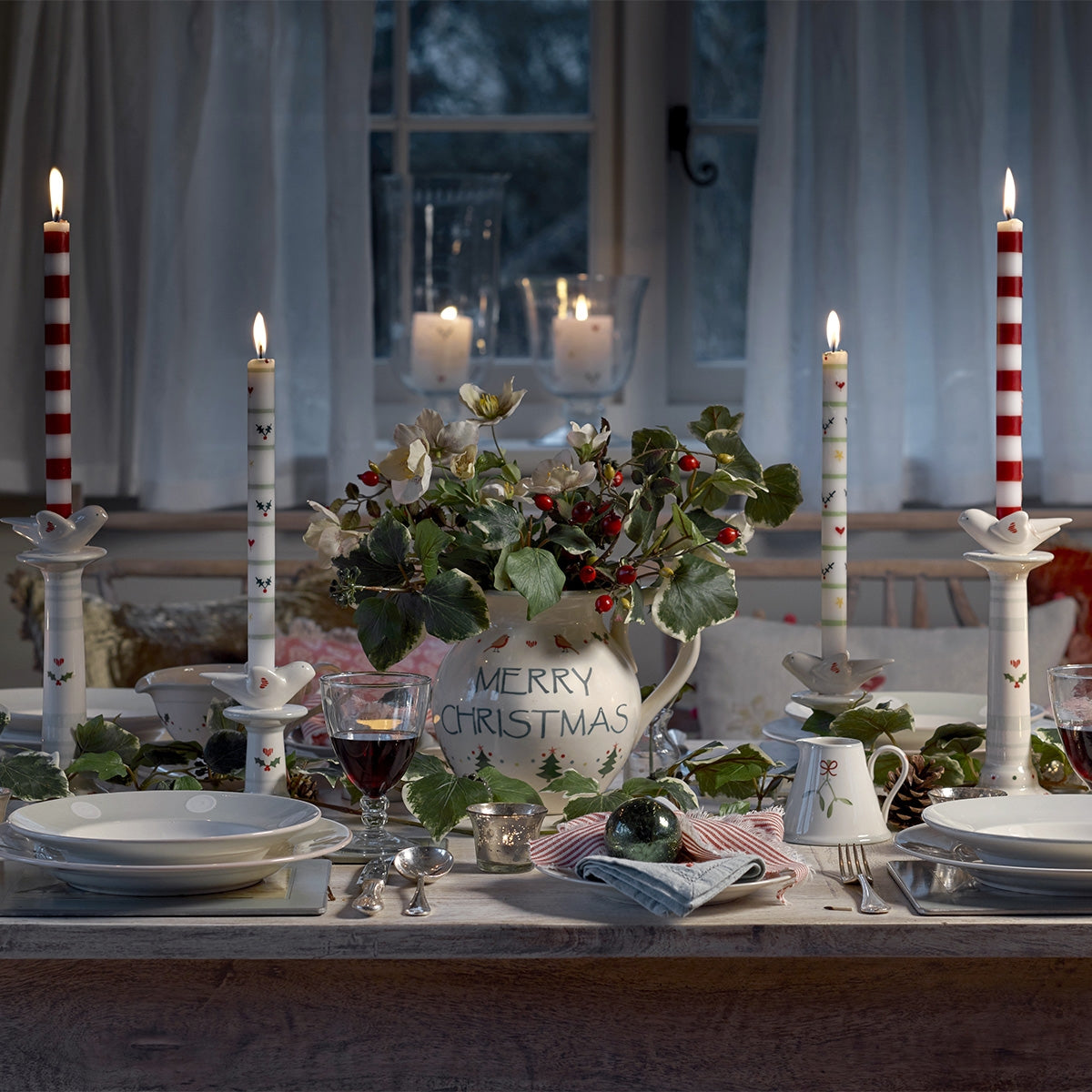 Christmas table with red striped candles, holly and the bird candlesticks