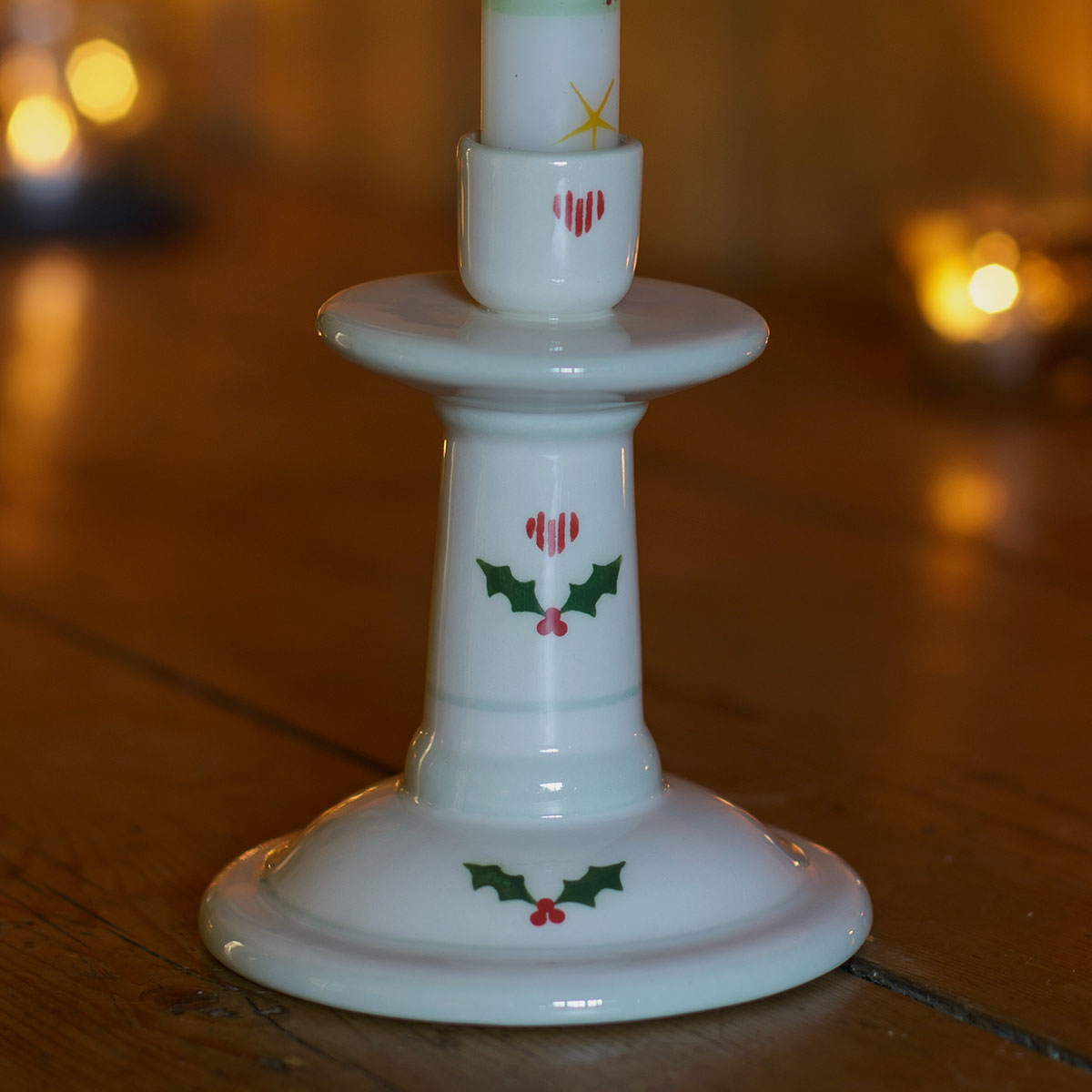 Small hand-decorated Christmas candlestick with holly and a red candle