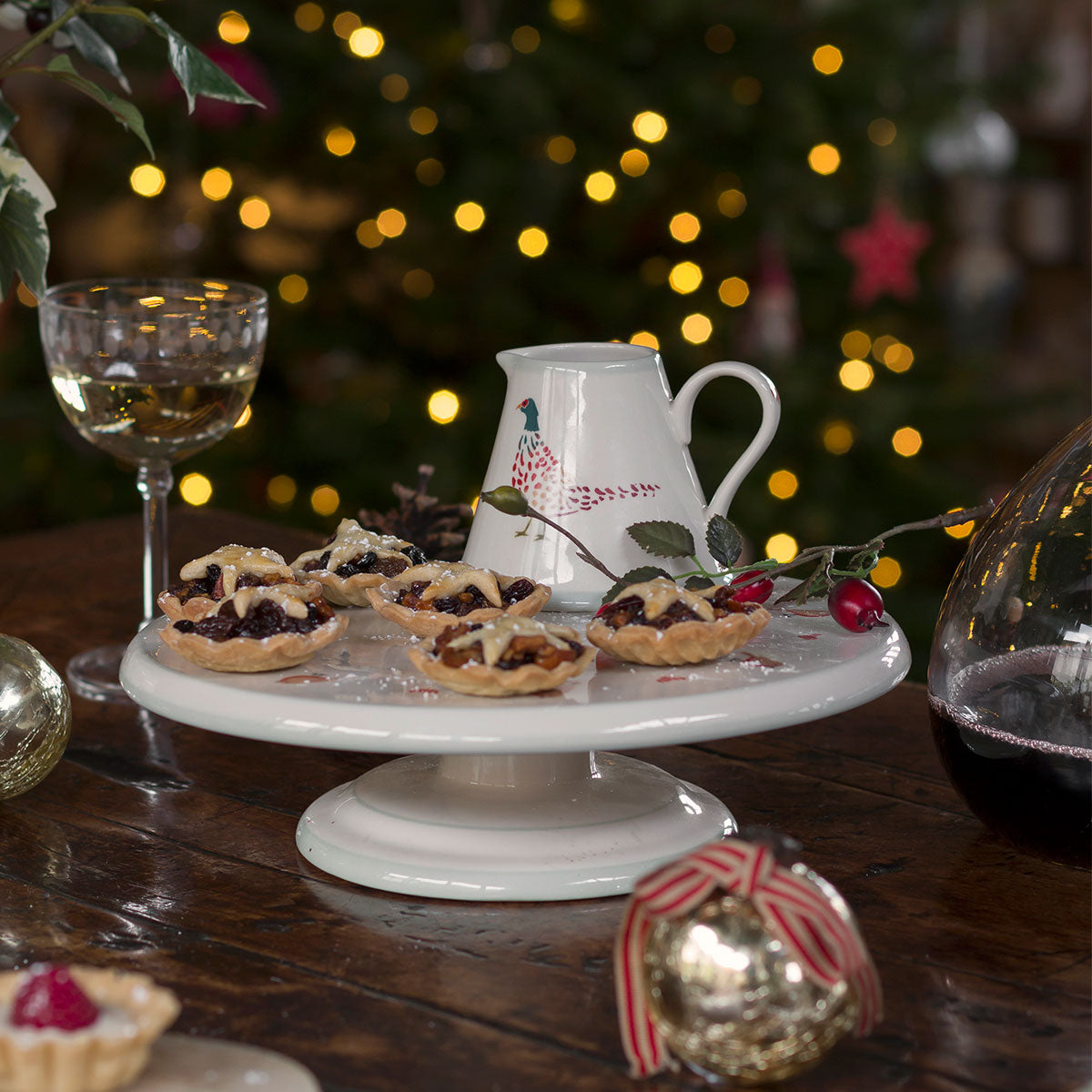Robin cake stand of mince pies before a lit Christmas tree
