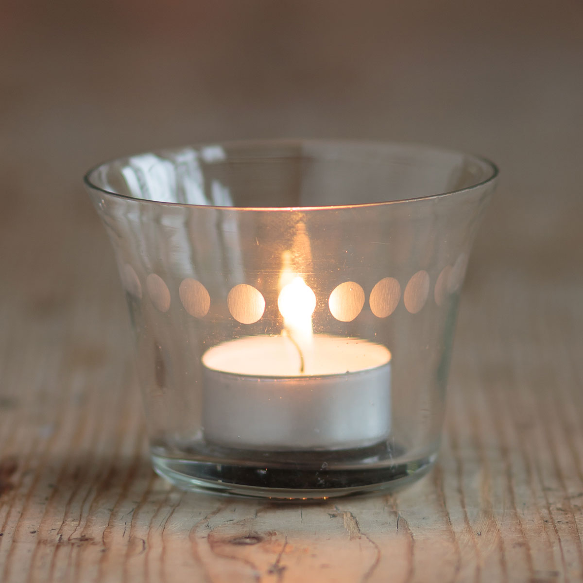 Lit tealight glowing inside the glass candlepot, close view