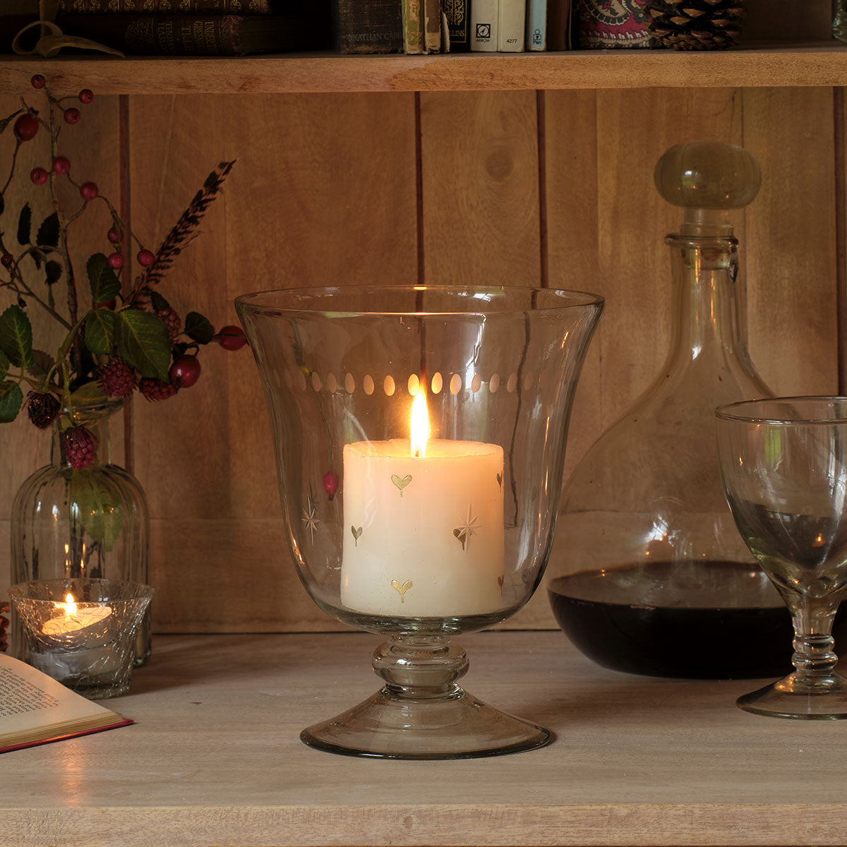 Gold Heart candle in a hurricane beside decanters by candlelight