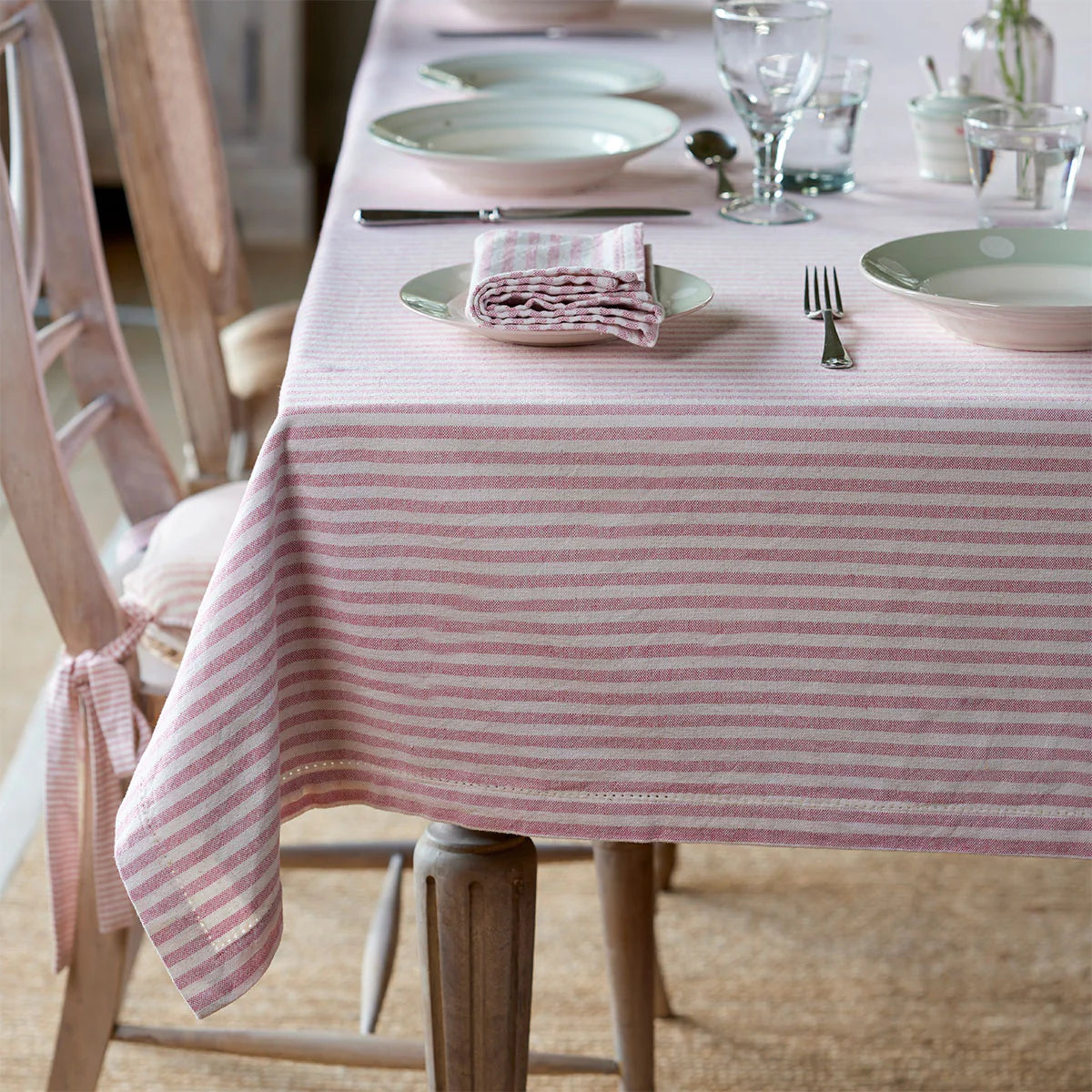 Rose ivory stripe tablecloth on a table laid with plates and glasses
