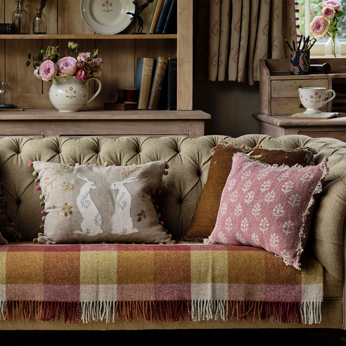 Megha cushions on a bench with a checked throw and dresser behind