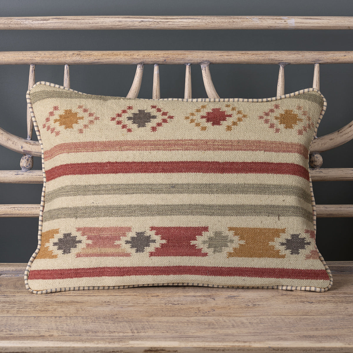 Saffron stripe kilim cushion with smokey blue accents on a bench